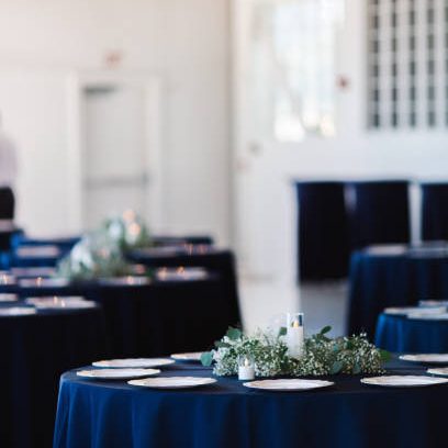 Event Tables with blue table cloths at a formal social gathering such as a wedding or birthday part or celebration of some sort.